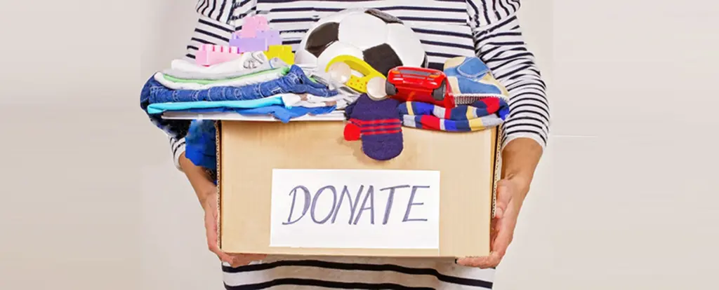 A volunteer packing unwanted clothes into a box for charity donation