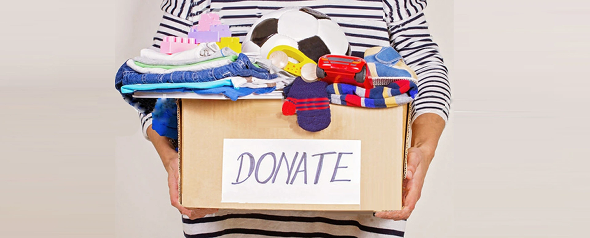A volunteer packing unwanted clothes into a box for charity donation