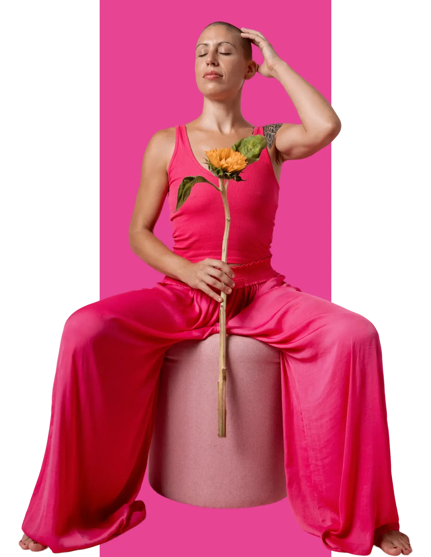 Woman with breast cancer holding a yellow flower sat on a stool